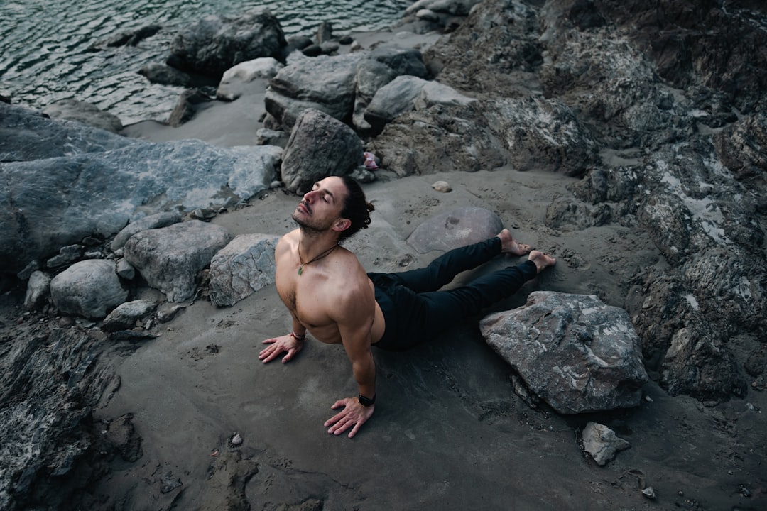 a-shirtless-man-laying-on-a-rocky-beach-hgiznbbm8y0